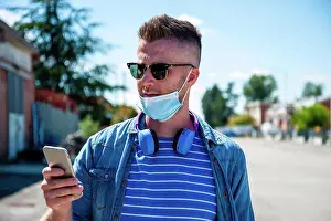 Network Prints: Cool guy wearing protective face mask standing outdoors while video calling his friends - Contemporary man having fun