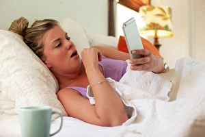 Fever Prints: Coughing young woman in her bed with using smartphone to check in with doctor