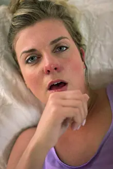 Fever Prints: Coughing young woman in her bed with using smartphone to check in with doctor