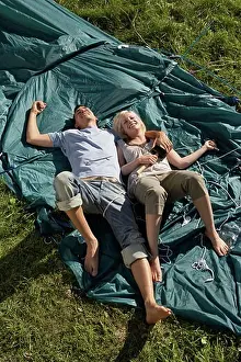 Tent Prints: Couple lying on unraised tent smiling with the woman holding mallet