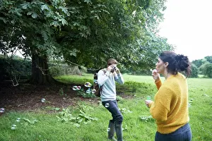 Grownups Prints: Couple playing with soap bubbles in field