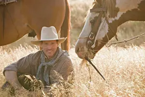 Wild West Prints: A cowboy sitting in long grass with two horses