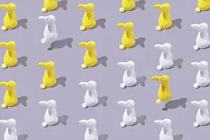 Composition Prints: Creative pattern with yellow and white plastic bunny on grey bac