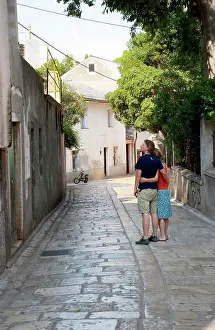 Strolling Prints: Cres, Coatia - Young couple stopped on a walkway in an Old World town. (MR)