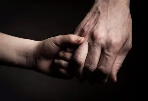 Midadult Men Prints: Cropped image of father and son holding hands against black background
