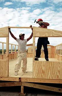 A Cuban migrant carpenter hammers in the nails as another migrant holds the frame during the construction of hard back
