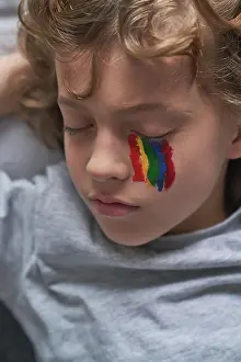 Paint Prints: From above cute boy in pajama and with rainbow under eye lying on pillow and blanket