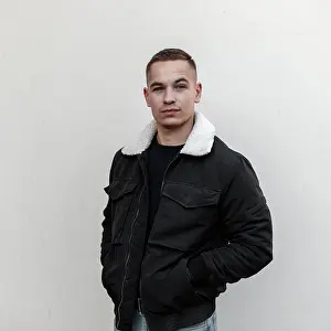 Augen Prints: Cute modernen jungen Mann mit einer stilvollen Frisur in Vintage Blue Jeans in einem trendigen schwarzen Jacke mit