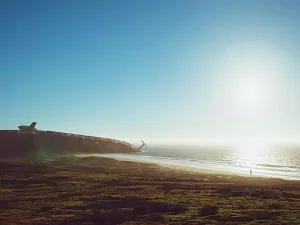 Sun Light Prints: Damaged old submarine at seashore against clear sky on sunny day