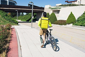 Handicapped Prints: Delivery man with prosthetic leg wheeling bicycle on footpath