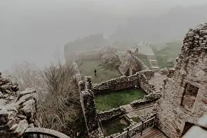 Mystery Prints: Destroyed old stone castle with fog with walls and stairs with tower on cloudy day
