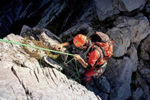 45 To 50 Years Prints: Determinant male Hiker moving down from mountain with rope on sunny day