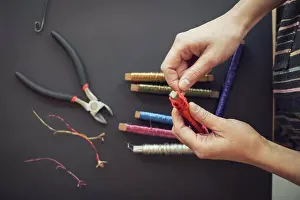 Mature Adult Prints: Directly above shot of woman rolling wire on spool at table