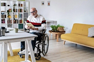 Handicapped Prints: Serious disabled man holding diary at home office