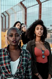 Diverse Prints: Diverse group of female friends wearing clothes in hipster style looking at camera seriously standing in urban area