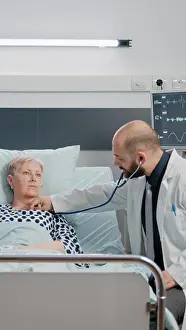 Hospital Ward Prints: Doctor consulting sick patient with stethoscope in hospital ward