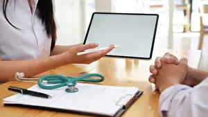 Typing Prints: Doctor using computer tablet discussion something with patient
