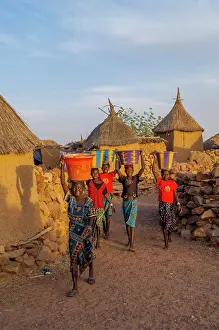 Evening Light Prints: Dogon girls bringing water from a community well back to their homes in the Djiguibombo Dogon village in the Bandiagara