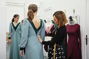 Apparel Prints: Dressmaker fitting custom gown on back of female client while working in professional workshop