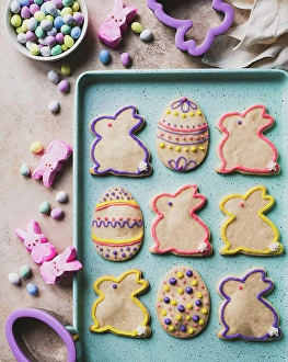 Easter cookies shaped like eggs and bunnies on green tray from above