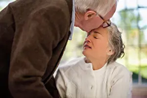 Relationships Prints: Elderly man kisses his wife on the forehead