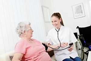 Disability Prints: Elderly senior woman with young doctor having medical care at home