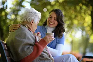 Weather Prints: Elderly woman enjoying cup of coffee with her nurse in the park during warm autumn day