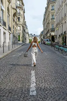Parisian Prints: Elegant woman walking up a charming cobblestone street in Paris