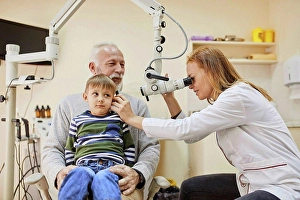 Competence Prints: ENT physician examining ear of a boy sitting on grandfather's lap