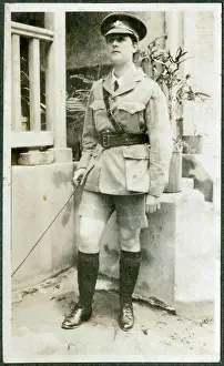 Cane Prints: A European woman poses outside a brick-built house dressed up in army uniform and carrying a cane