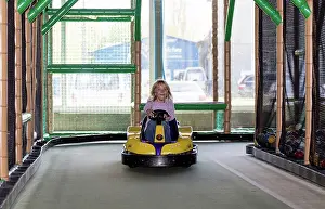 Leisure Wear Prints: Excited little girl driving bumper car in an indoor playground