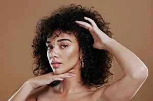 Face, skincare and hair with a model black woman in studio on a brown background for natural keratin treatment