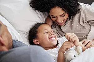 Joke Prints: Family, laughing and care on bed with smile for wellness