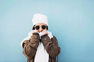 Colored Background Prints: Fashionable woman wearing warm clothing standing against blue background