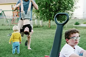 Small Group Prints: Father and boys playing in a suburban backyard in the summer