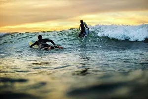 Midadult Men Prints: Father and daughter surfing at sunset