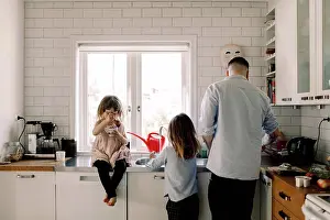Frgbild Prints: Father and daughter working while girl eating food in kitchen at home