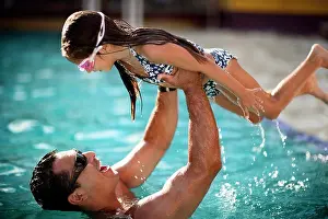 Dads Prints: Father holds his daughter aloft at a swimming pool