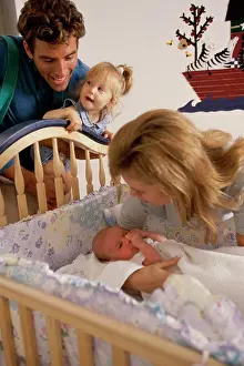 Beginnings Prints: Father and mother looking at their baby in a crib