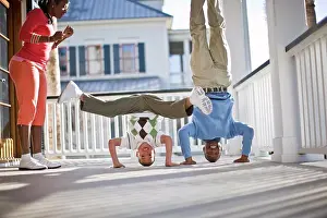 30 To 35 Years Prints: Father and son breakdancing on deck with mother watching