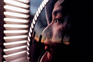 Glass Material Prints: Female astronaut looking at illuminated lights while wearing space helmet