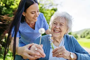 Assisted Prints: Female caregiver and senior woman in wheelchair holding dandelion