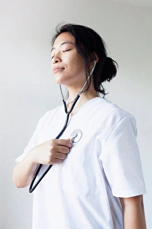 Adult Sonly Prints: Female doctor listening self heart beat with stethoscope against wall