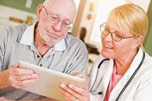 Doctors Prints: Female doctor or nurse showing senior man touch pad computer at home