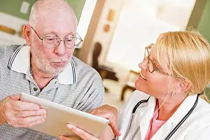 Doctors Prints: Female doctor or nurse showing senior man touch pad computer at home