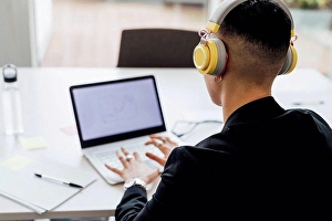 Business Women Prints: Female entrepreneur with headphones working on laptop in office