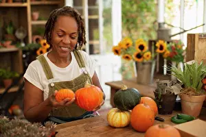 Tilt Prints: Female florist arranging autumn pumpkins in shop