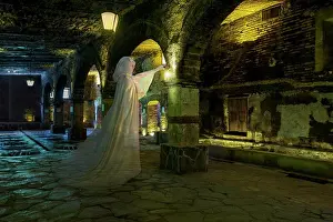 Halloween Prints: Female ghost with lantern, dressed all in white standing in a cavernous stone basement
