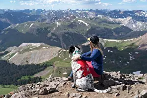 Getaway Prints: Female hiker sitting on mountain with dog during sunny day
