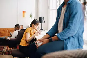 Using Phone Prints: Female programmer using mobile phone on desk while sitting in office